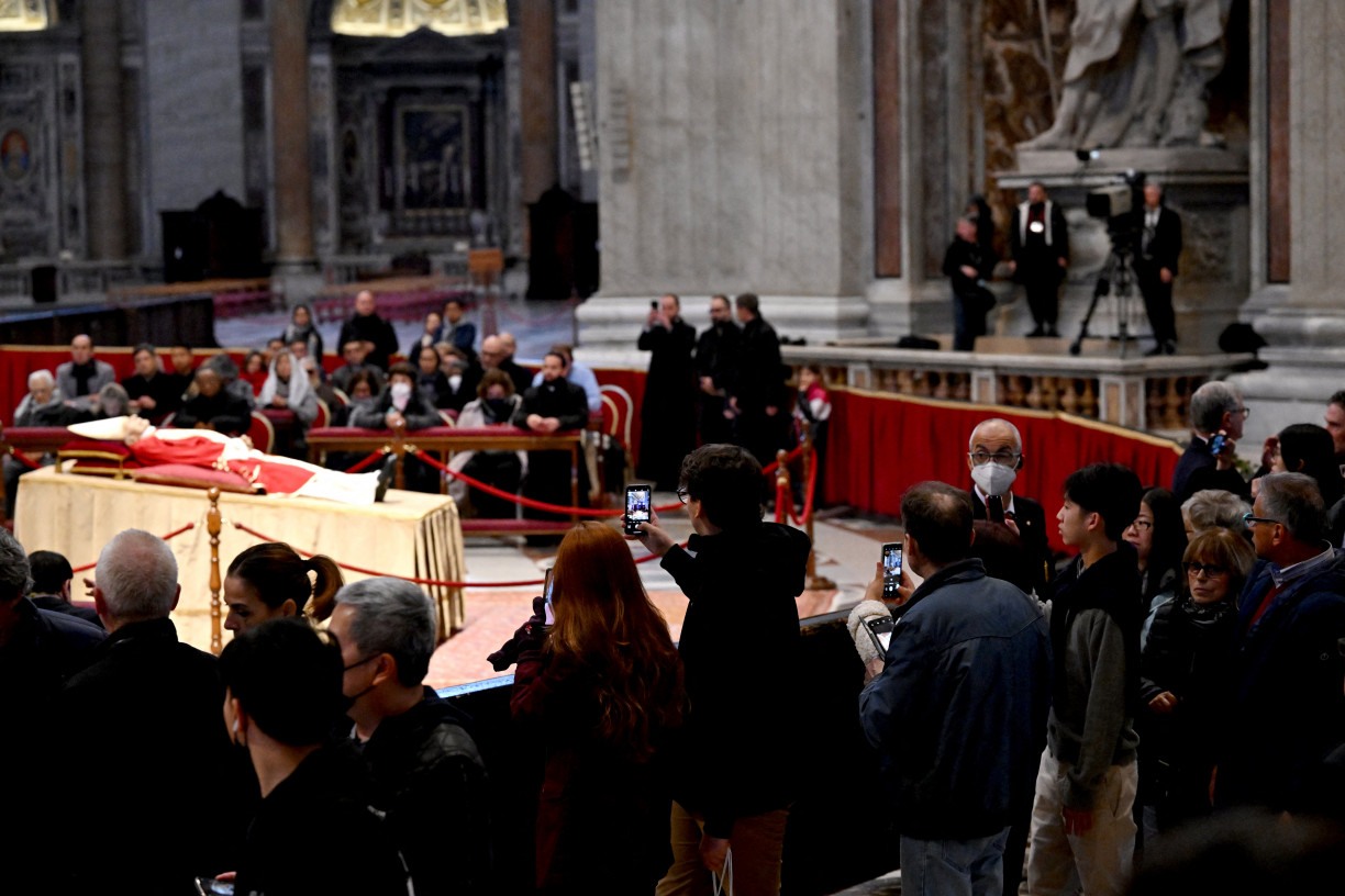 Os fiéis entram em silêncio pelo corredor central do maior templo católico do mundo, a maioria fotografando com seus celulares o corpo do papa emérito. -